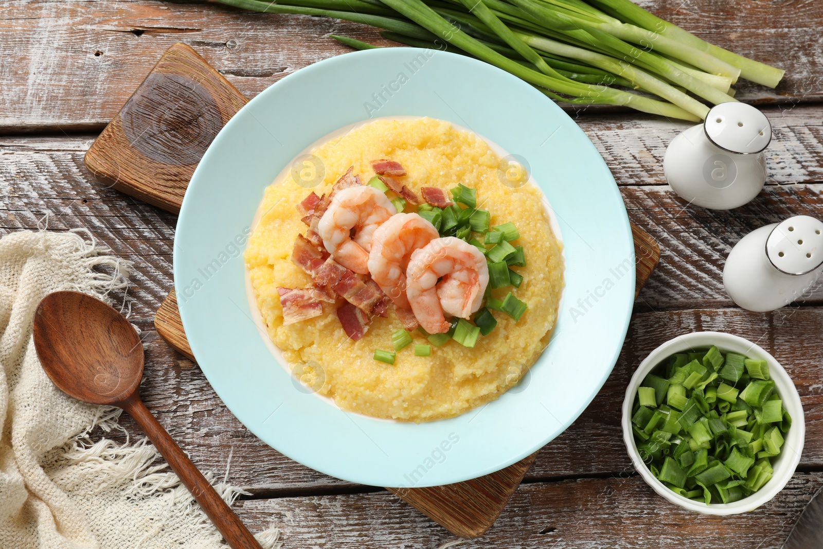 Photo of Plate with fresh tasty shrimps, bacon, grits and green onion on wooden table, flat lay