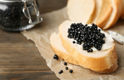 Photo of Sandwich with black caviar on wooden background