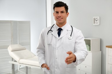 Happy male doctor offering handshake in clinic