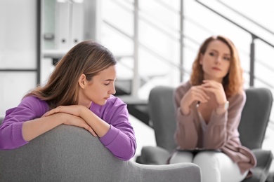 Photo of Child psychologist working with teenage girl in office