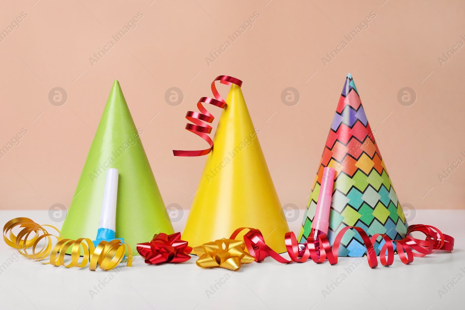 Photo of Colorful party hats, streamers and blowers on white table. Birthday celebration