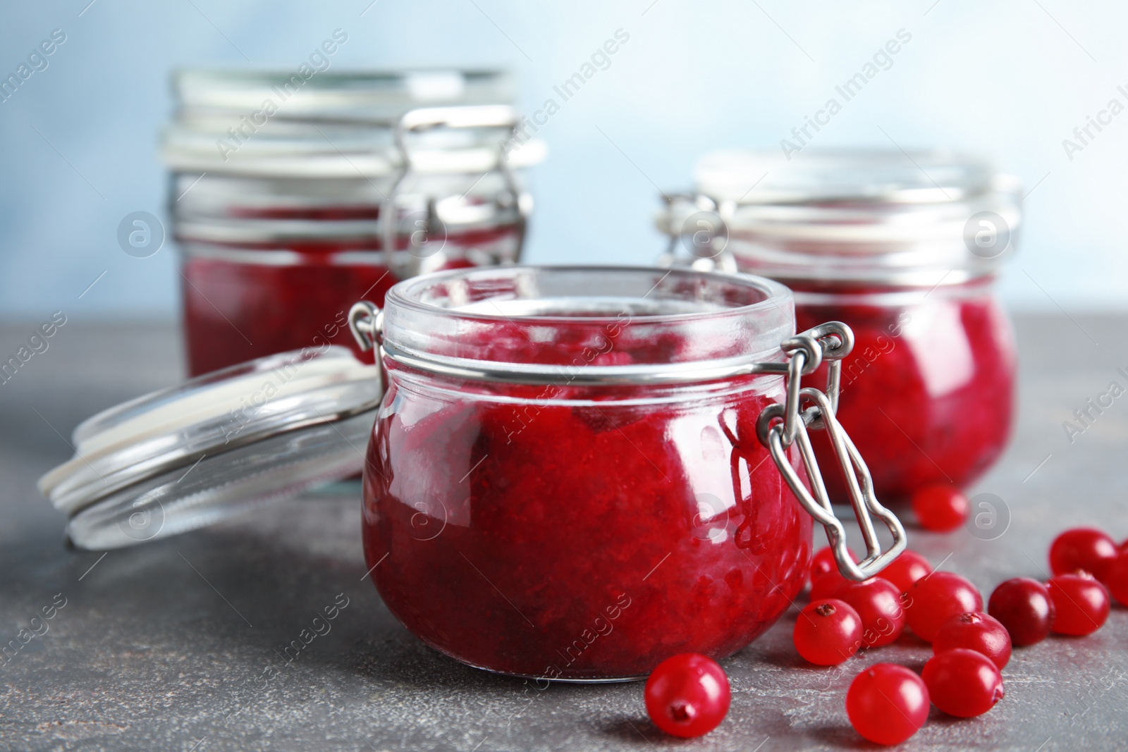 Photo of Glass jars with cranberry sauce on table, closeup