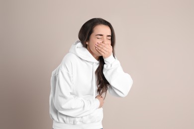 Young woman suffering from stomach ache and nausea on beige background. Food poisoning