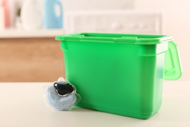 Laundry container and washing detergent capsule on table indoors