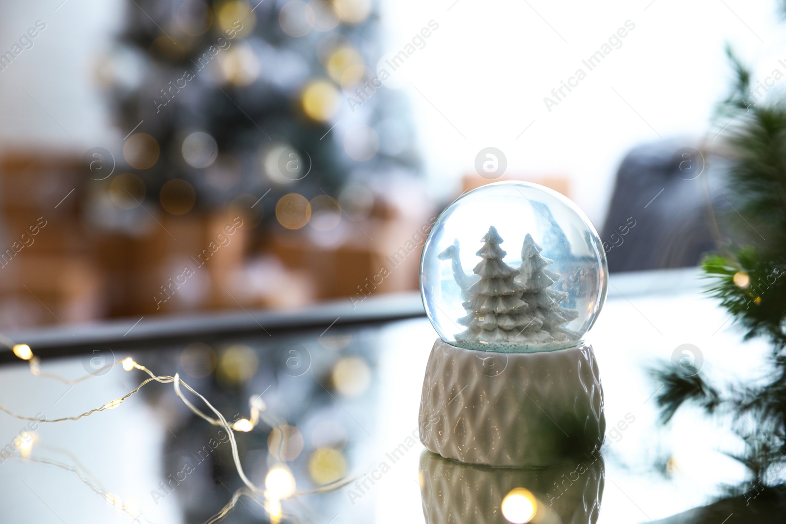 Photo of Decorative Christmas snow globe on mirror surface indoors