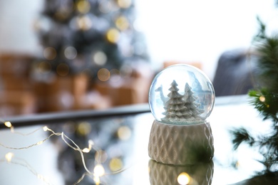 Photo of Decorative Christmas snow globe on mirror surface indoors