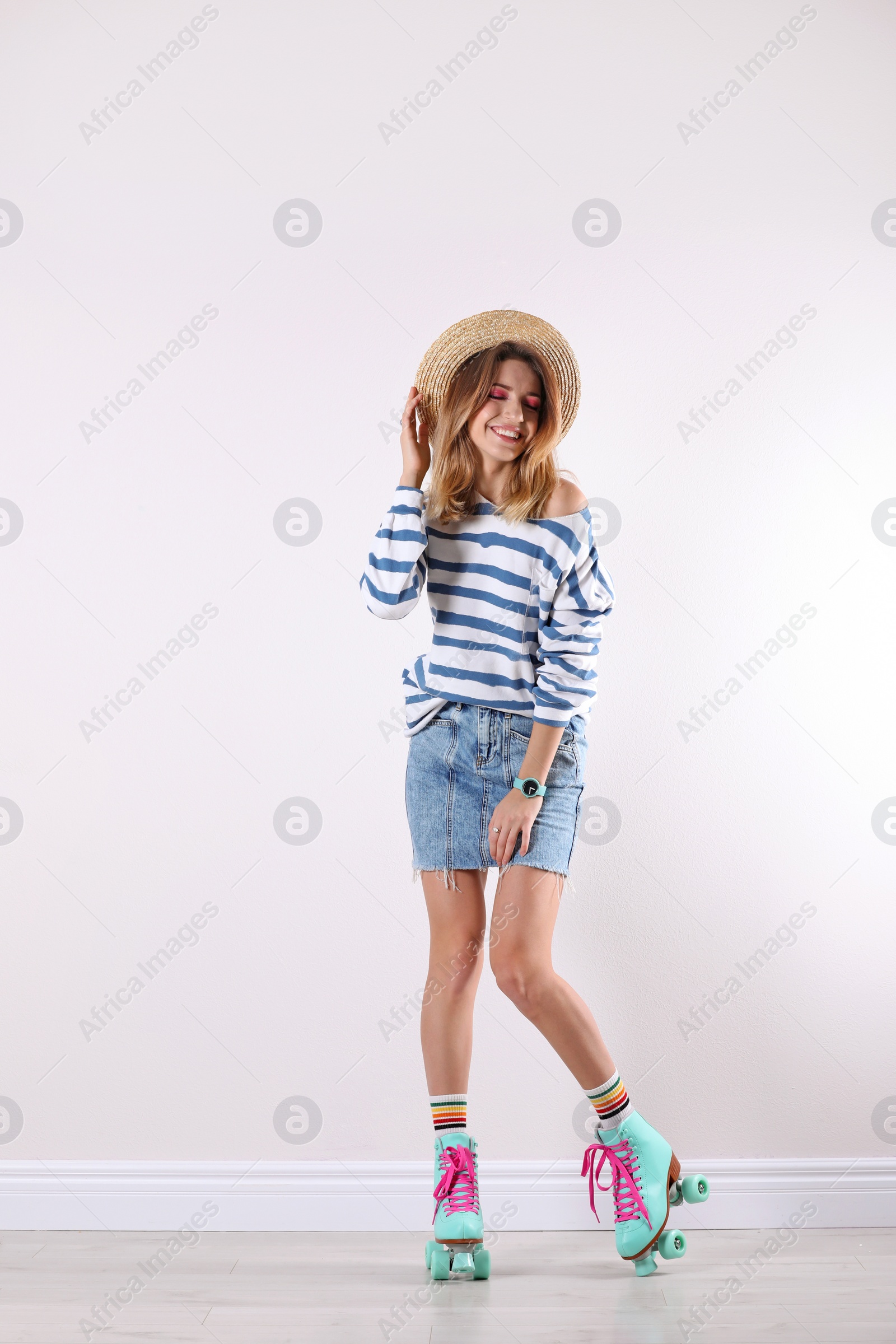 Photo of Young woman with retro roller skates near white wall