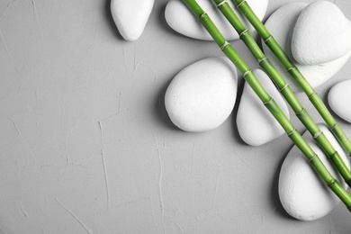 Photo of Zen stones and bamboo on grey background, top view with space for text