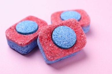 Photo of Dishwasher detergent tablets on pink background, closeup