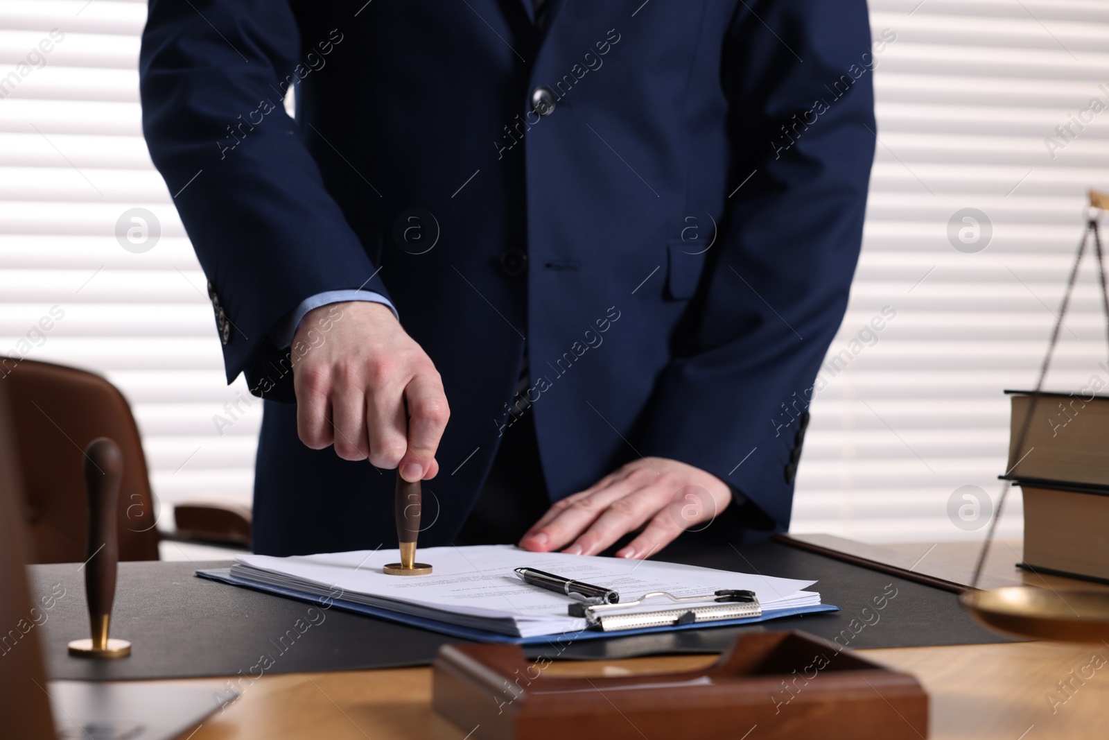 Photo of Notary stamping document at table in office, closeup