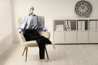 Waiting concept. Human skeleton sitting in armchair at office, space for text