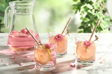 Photo of Refreshing drink with lemon and rose on white marble table