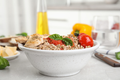 Tasty buckwheat porridge with meat and vegetables on grey marble table indoors