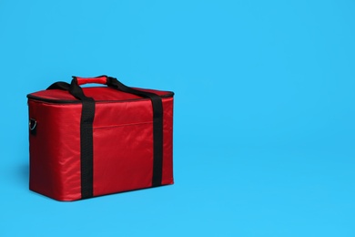 Photo of Modern red thermo bag on light blue background. Space for text