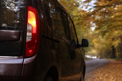 Photo of Modern car parked near autumn forest, closeup