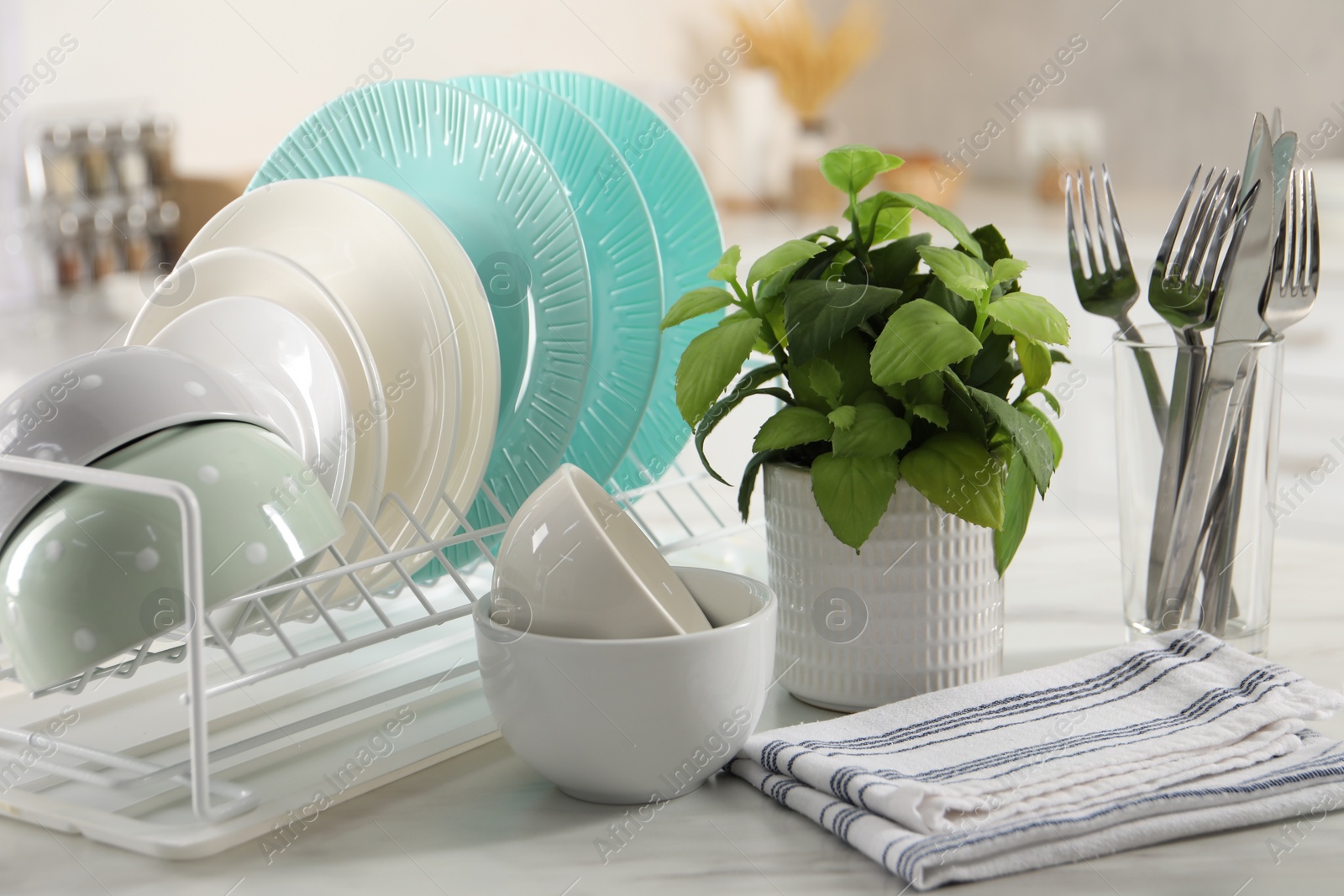 Photo of Many different clean dishware, cutlery and houseplant on white marble table in kitchen