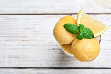 Yummy lemon ice cream in dessert bowl on wooden table, top view. Space for text