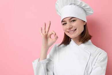 Photo of Professional chef showing OK gesture on pink background. Space for text