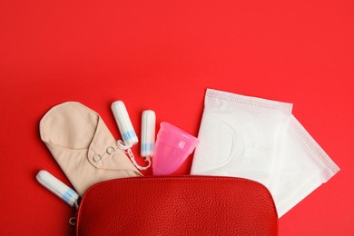 Photo of Tampons and other menstrual hygienic products on red background, flat lay