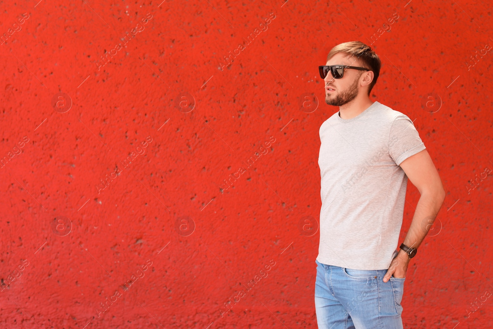 Photo of Young man wearing gray t-shirt near color wall on street