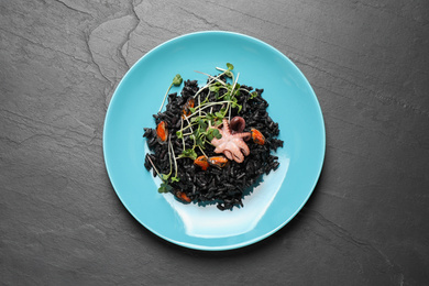 Delicious black risotto with seafood on grey table, top view