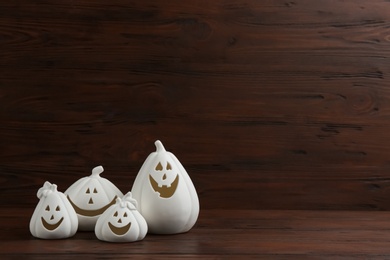 Photo of Jack-o-Lantern candle holders on table against wooden background, space for text. Halloween decor