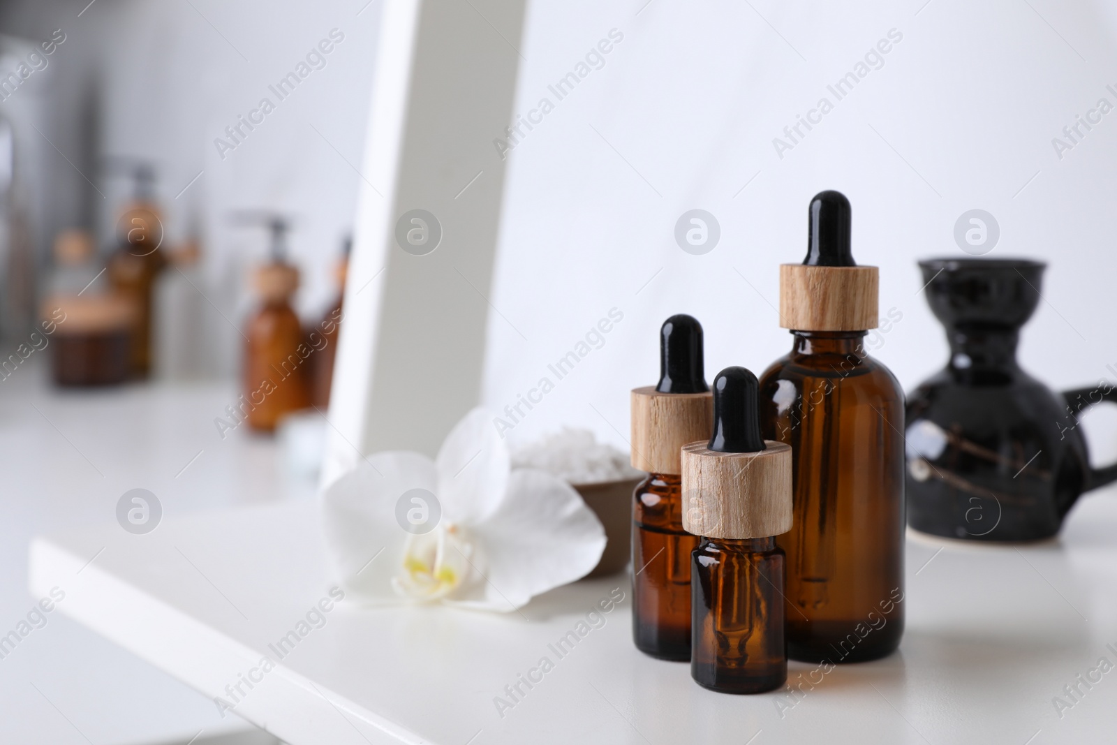 Photo of Bottles of essential oil on white shelf in bathroom. Space for text