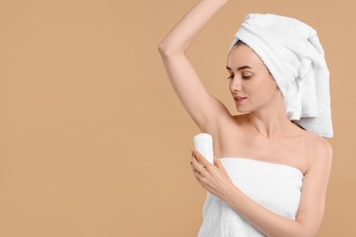 Photo of Beautiful woman applying deodorant on beige background, space for text