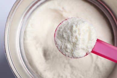 Photo of Scoop of powdered infant formula over can, top view. Baby milk