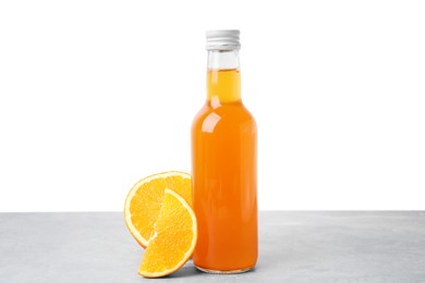 Photo of Delicious kombucha in glass bottle and orange on grey table against white background