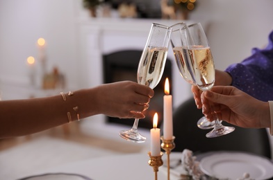 Photo of People clinking glasses with champagne at home, closeup