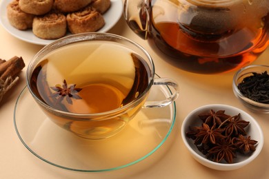 Aromatic tea with anise stars on beige background, closeup