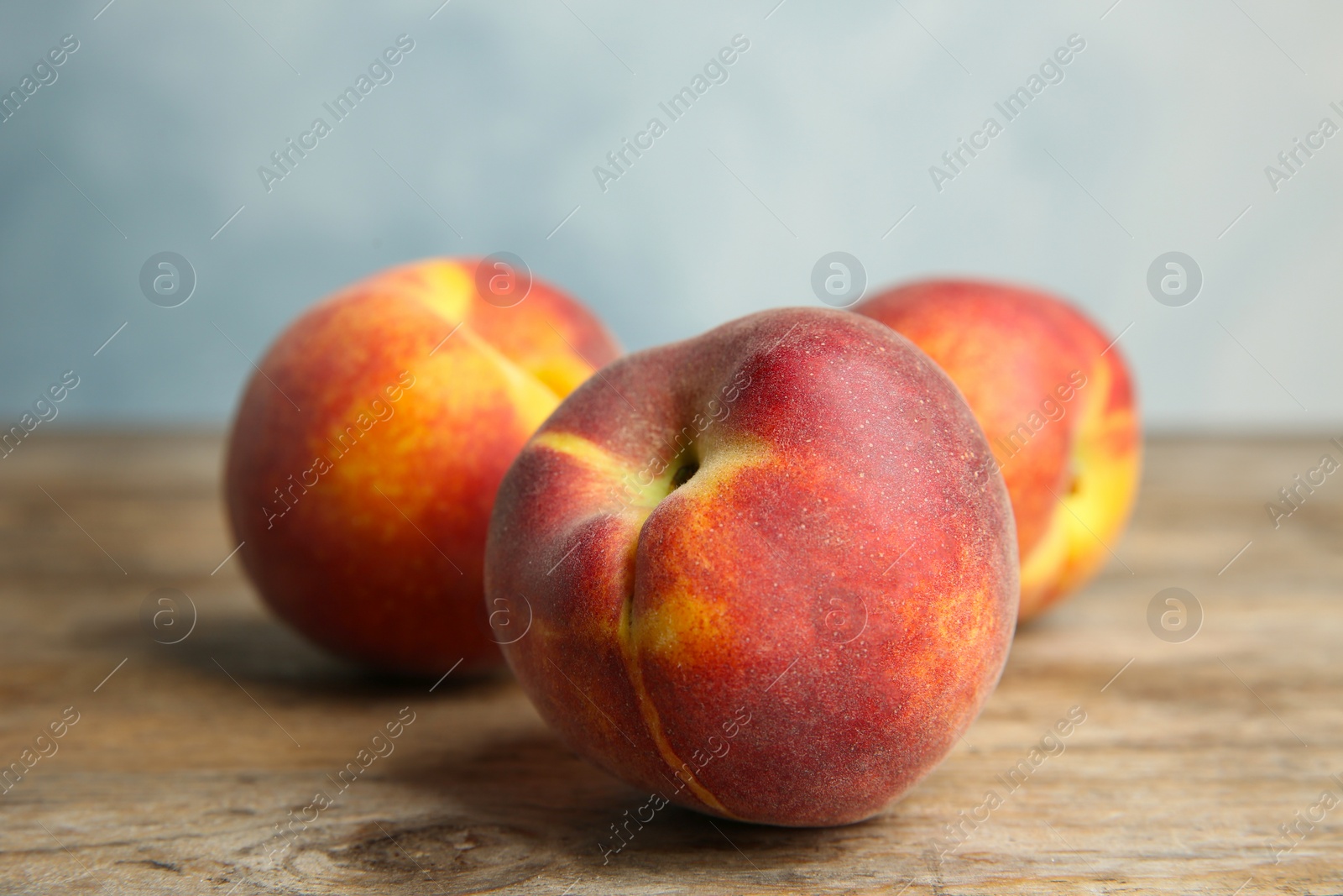 Photo of Fresh juicy peaches on wooden table against blue background