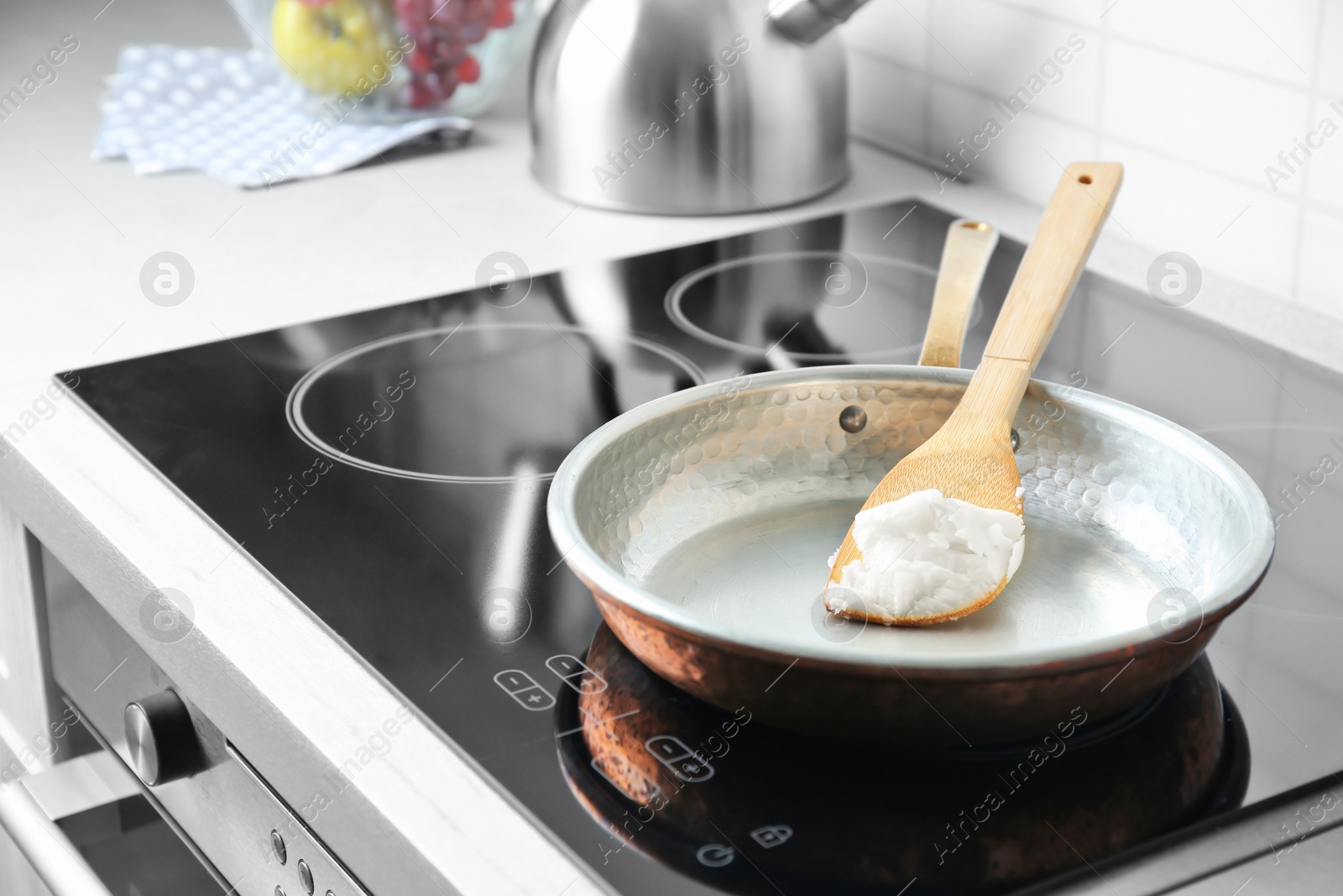 Photo of Wooden spatula with coconut oil in frying pan. Healthy cooking