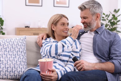 Photo of Happy affectionate couple with popcorn on sofa indoors. Romantic date