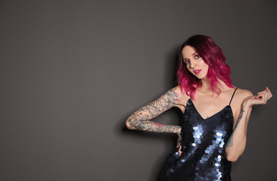 Photo of Beautiful woman with tattoos on arms against black background. Space for text