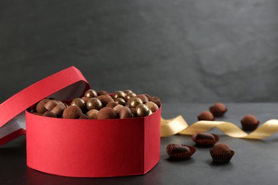 Photo of Different delicious chocolate candies in box on black table