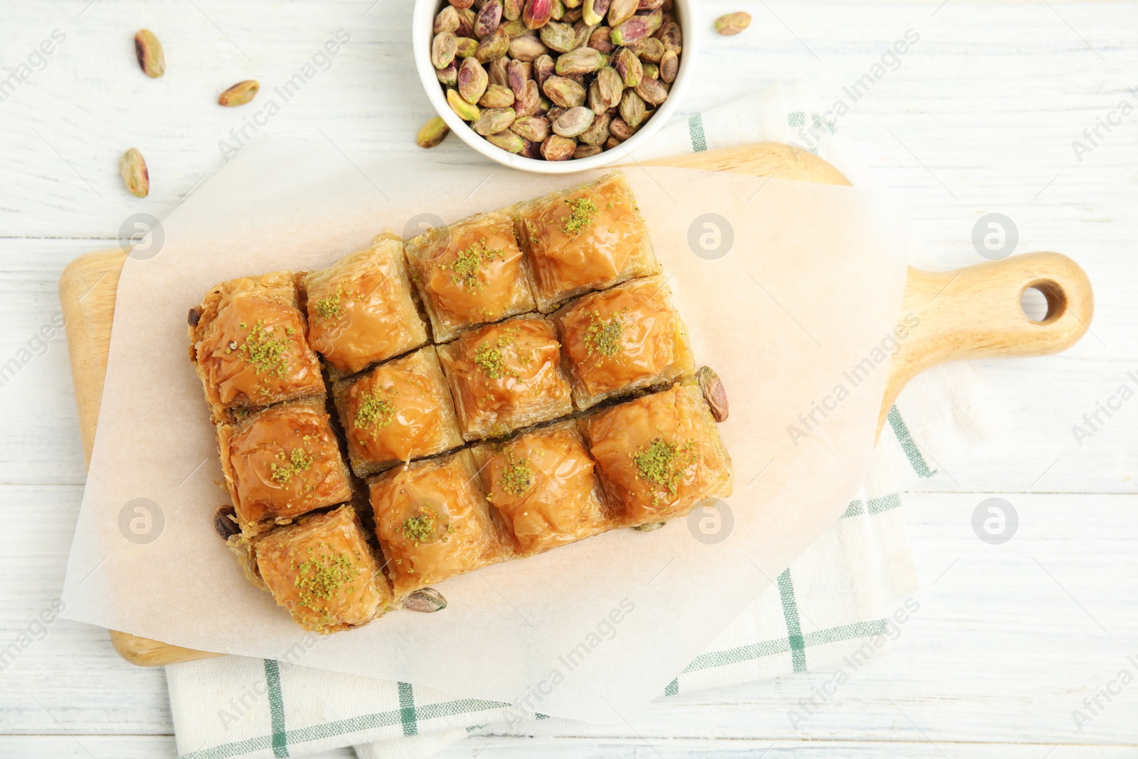 Photo of Delicious sweet baklava with pistachios on white wooden table, flat lay