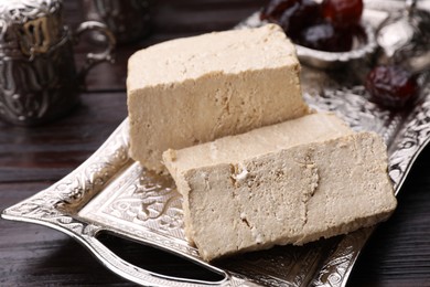 Pieces of tasty halva served on vintage tray on wooden table, closeup