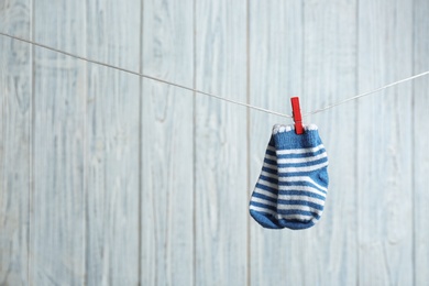 Pair of socks on laundry line against wooden background, space for text. Baby accessories