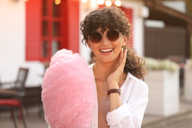 Portrait of smiling woman with cotton candy outdoors on sunny day