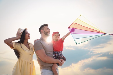 Photo of Happy parents and their child playing with kite on sunny day. Spending time in nature