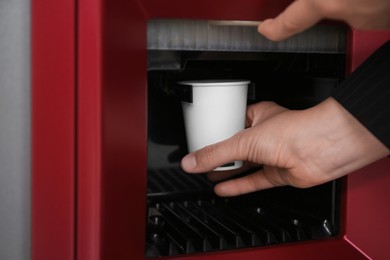 Photo of Woman taking paper cup with coffee from vending machine, closeup
