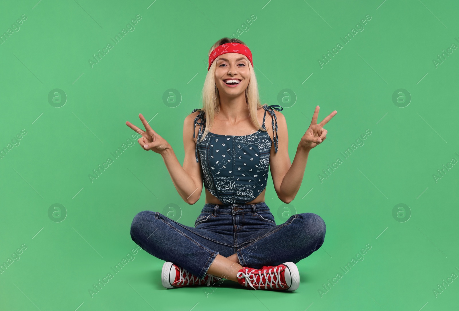 Photo of Portrait of happy hippie woman showing peace signs on green background
