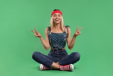 Photo of Portraithappy hippie woman showing peace signs on green background
