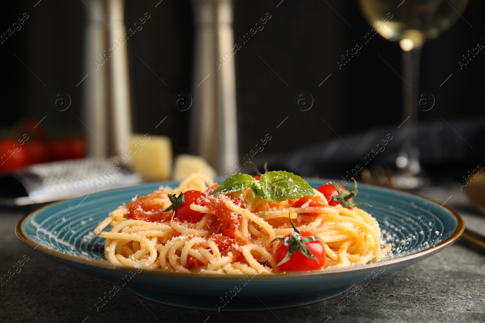 Photo of Tasty pasta with basil, tomatoes and cheese on grey table. Closeup