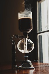 Photo of Vacuum coffee maker on wooden table in cafe