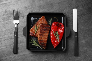 Photo of Grilled meat served with garnish on black table, flat lay