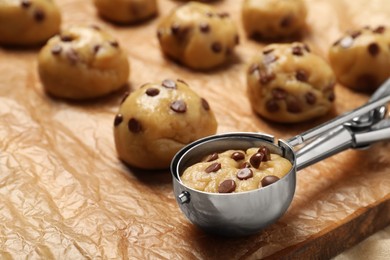 Photo of Uncooked chocolate chip cookies and scoop on parchment, closeup