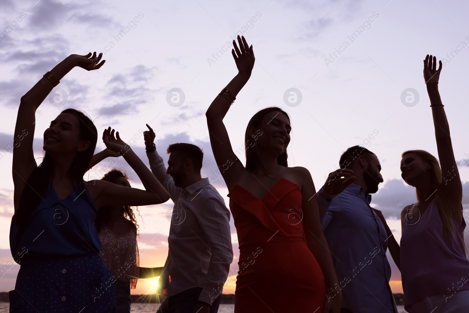 Photo of Group of friends having fun near river at sunset. Summer party